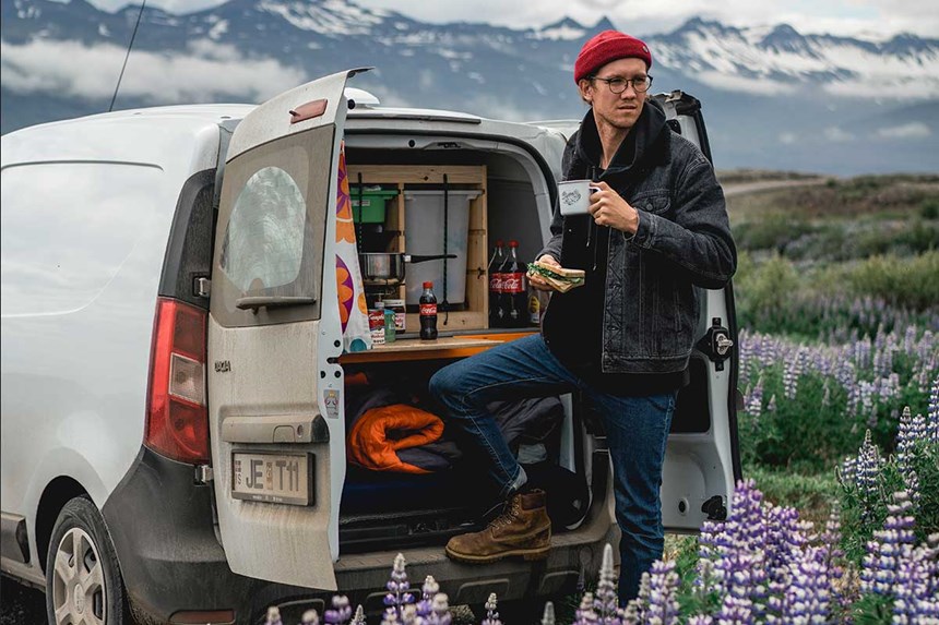 a man drinking morning coffee in iceland in his campervan