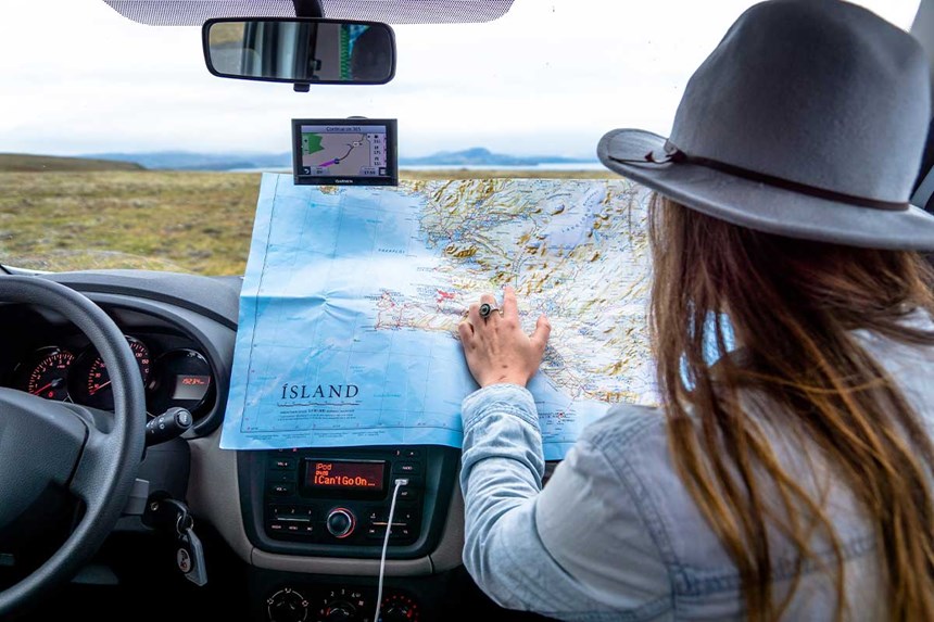 a woman looking at an icelandic map in her campervan